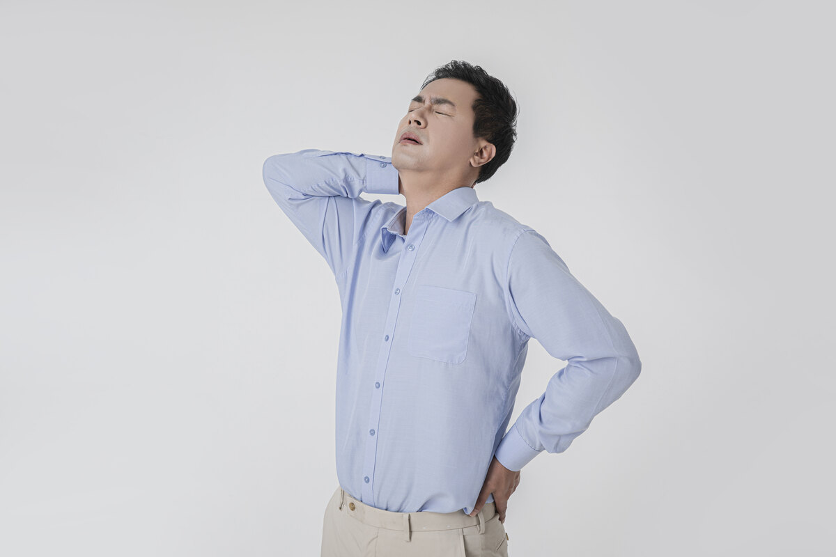 목 뒤쪽을 손으로 짚으며 뻐근함을 호소하는 남성