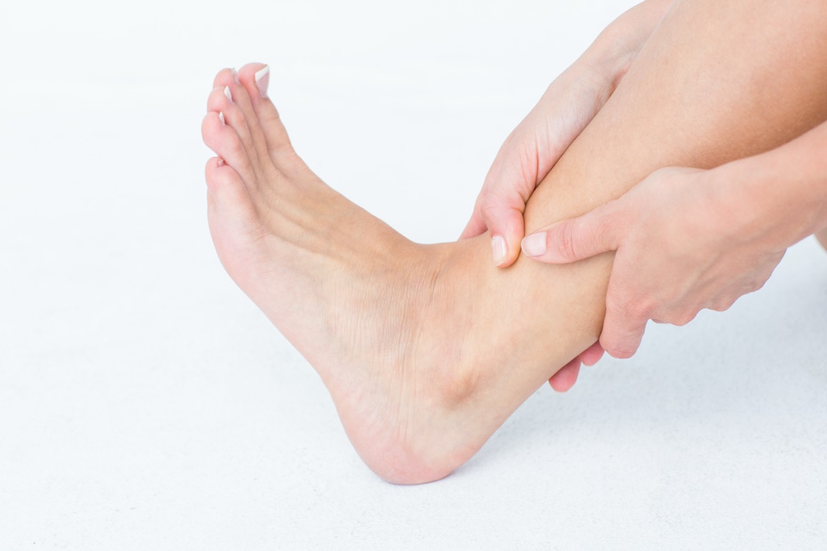 발목과 발등을 손으로 감싸 쥔 모습, 발톱 통증으로 걸음이 불편해진 상황