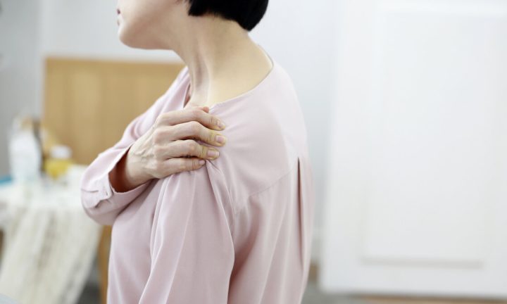 어깨를 손으로 감싸 쥔 중년 여성 — 오십견 통증